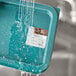 A blue container of Noble Products Thursday food labeling stickers with water being poured over it.