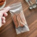 A hand holding a Clear Line seal top plastic food bag of cinnamon sticks.