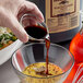 A hand pouring Lea & Perrins Worcestershire sauce into a bowl of food.
