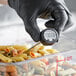 A person in black gloves using an AvaTemp digital pocket probe thermometer to check the temperature of pasta.