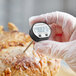 A person holding a black AvaTemp digital pocket probe thermometer over a roast.