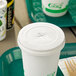 A white EcoChoice paper cold cup with a green compostable lid and a straw on a tray.