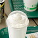 A white cup of whipped cream with a translucent dome lid with a hole on a tray.