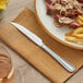 A plate of steak and fries with a Acopa stainless steel steak knife on a napkin.