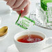 A hand holding a Splenda Stevia Naturals packet over a cup of tea.