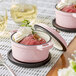 A pink Valor enameled cast iron pot with food in it.