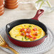A Valor Merlot enameled mini cast iron skillet with an omelette with bacon and cheese in it.
