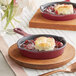 A Valor merlot enameled mini cast iron skillet with a biscuit and fruit on a wooden tray.