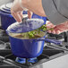 A person cooking food in a Valor Galaxy Blue enameled cast iron sauce pan.