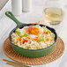A Valor fern green enameled cast iron skillet with noodles and vegetables.