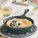 A Valor green enameled cast iron skillet with blueberries and cream on a table.