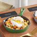 Two Valor fern green enameled mini cast iron skillets with poached eggs and potatoes.
