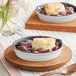 A Valor mini cast iron skillet with fruit cobbler on a wooden tray.