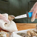 A person using a Choice Boston Style Oyster Knife with a blue handle to cut up oysters.
