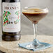 A glass of brown liquid flavored with Monin Premium Espresso Syrup next to a bottle of Monin syrup.
