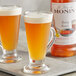 A bottle of Monin Premium Brown Butter flavoring syrup with a couple of glasses of liquid.