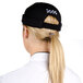 A woman with a ponytail wearing a black Chef Revival beanie with a white logo.