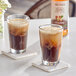 Two glasses of iced coffee with Monin Hazelnut Syrup on a table with coasters.