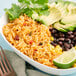 A bowl of Mexican rice with black beans, avocado, and lime.
