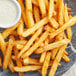 A plate of Lawry's Ranch French fries with a small bowl of white sauce.