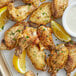 A tray of Lawry's Zesty Lemon and Pepper chicken wings with lemon slices and a bowl of white sauce.