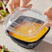 A hand using a Visions clear plastic dome lid to cover a bowl of food.
