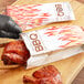 A person in gloves putting a piece of cooked meat in a Choice insulated foil BBQ bag.