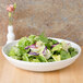 A CAC Super Bright White Porcelain bowl filled with salad with lettuce and purple cabbage.