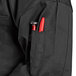 A black Uncommon Chef short sleeve chef coat with mesh back and a red pen in the pocket.