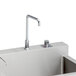 A stainless steel Elkay surgeon scrub sink with three bowls and hands-free operation faucets.