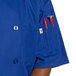 A man wearing a royal blue short sleeve chef coat with red buttons.