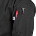 A person wearing a black Uncommon Chef long sleeve chef coat with a pen in the pocket.