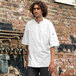 A man wearing a white Uncommon Chef Aruba Pro Vent chef coat with mesh back.