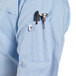 A man wearing a sky blue Uncommon Chef short sleeve chef coat with a pen in the pocket.