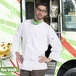 A man wearing a white Uncommon Chef 3/4 sleeve coat with yellow trim standing in front of a food truck.