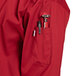 A red Uncommon Chef long sleeve chef coat with a pocket and pen holder.
