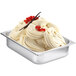 A metal tray of white ice cream with red berries on top.