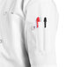 A person wearing a Uncommon Chef Montego Pro Vent white chef coat with a pen in the pocket.