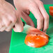 A person using a Dexter-Russell DuoGlide utility knife to cut a tomato.