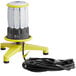 A yellow and white Lind Equipment Beacon360 Blaze portable LED area light on a floor stand with a black cord.