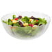 An Arcoroc glass bowl filled with salad greens, croutons and vegetables.