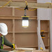 A man using a Lind Equipment Beacon360 Blaze LED portable jobsite light to work on a piece of wood.