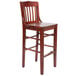A Lancaster Table & Seating mahogany wood school house bar stool with a wooden seat.