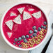 A bowl of pink smoothie with blueberries and dragon fruit cubes.
