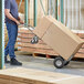 A man using a Lavex 2-in-1 hand truck to move a large box.
