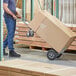 A man in blue jeans pushing a Lavex 2-in-1 hand truck with a box.