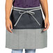 A woman wearing a black and grey Uncommon Chef waist apron.