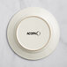 An ivory stoneware plate with the word Acopa embossed on the rim.
