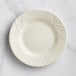An Acopa Swell ivory stoneware plate with an embossed wavy design.