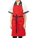 A woman wearing a red Uncommon Chef apron with black webbing.